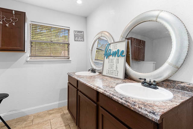 bathroom featuring baseboards, a sink, and double vanity
