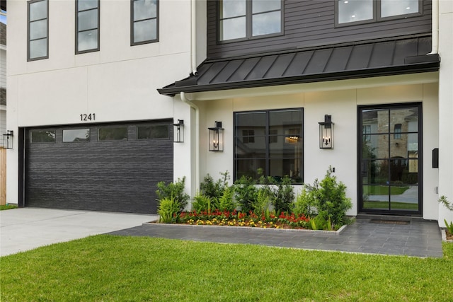 entrance to property with a standing seam roof, metal roof, concrete driveway, a lawn, and stucco siding