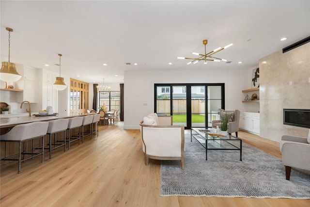 living area with light wood-style floors, an inviting chandelier, recessed lighting, and plenty of natural light