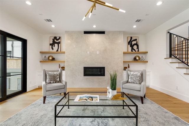 living area featuring recessed lighting, stairway, visible vents, light wood-style floors, and a premium fireplace
