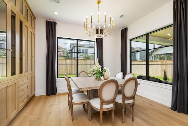 dining room featuring light wood-style flooring, visible vents, baseboards, and a notable chandelier