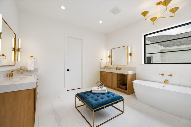 full bath with a sink, walk in shower, a freestanding bath, two vanities, and recessed lighting