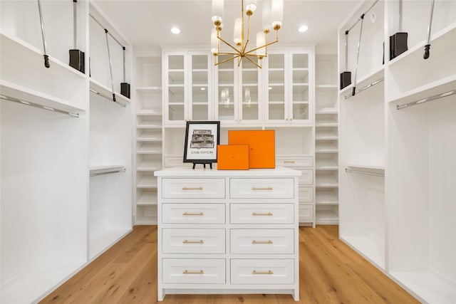 walk in closet featuring a chandelier and light wood-style floors
