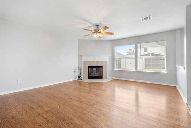 8027 Lavage Ln, Baytown, TX 77521 - unfurnished living room with light wood-type flooring, baseboards, visible vents, ceiling fan, and a fireplace