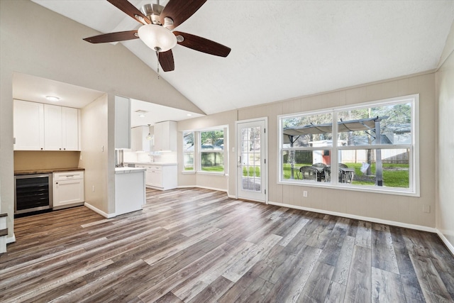 unfurnished living room featuring wood finished floors, a ceiling fan, plenty of natural light, and wine cooler