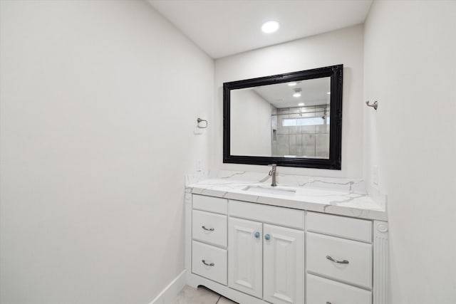 bathroom with baseboards, vanity, and recessed lighting