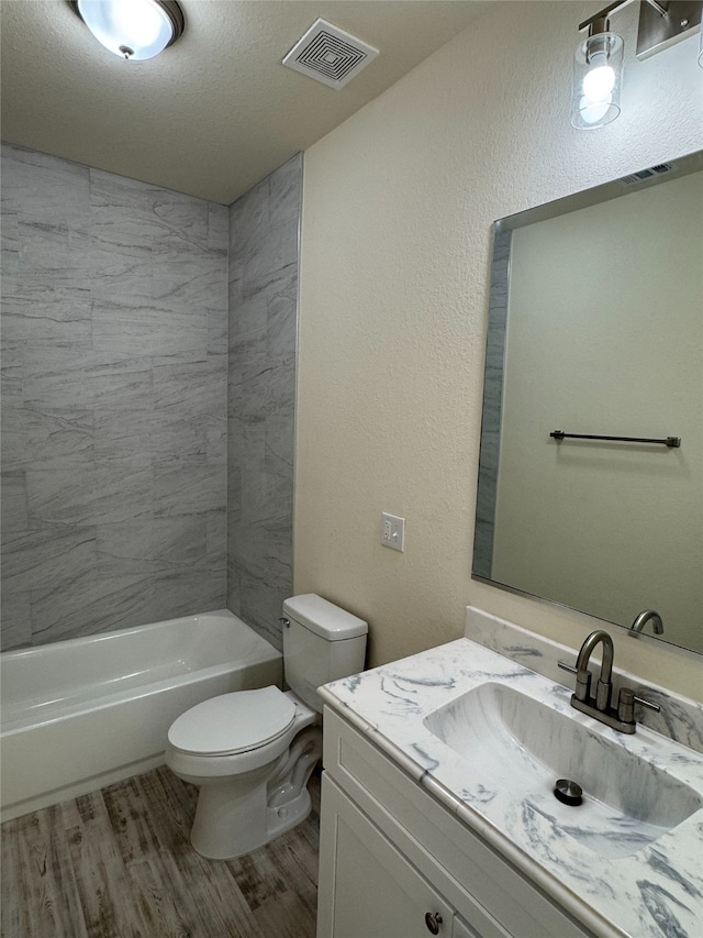 bathroom with wood finished floors, visible vents, toilet, vanity, and shower / bathing tub combination