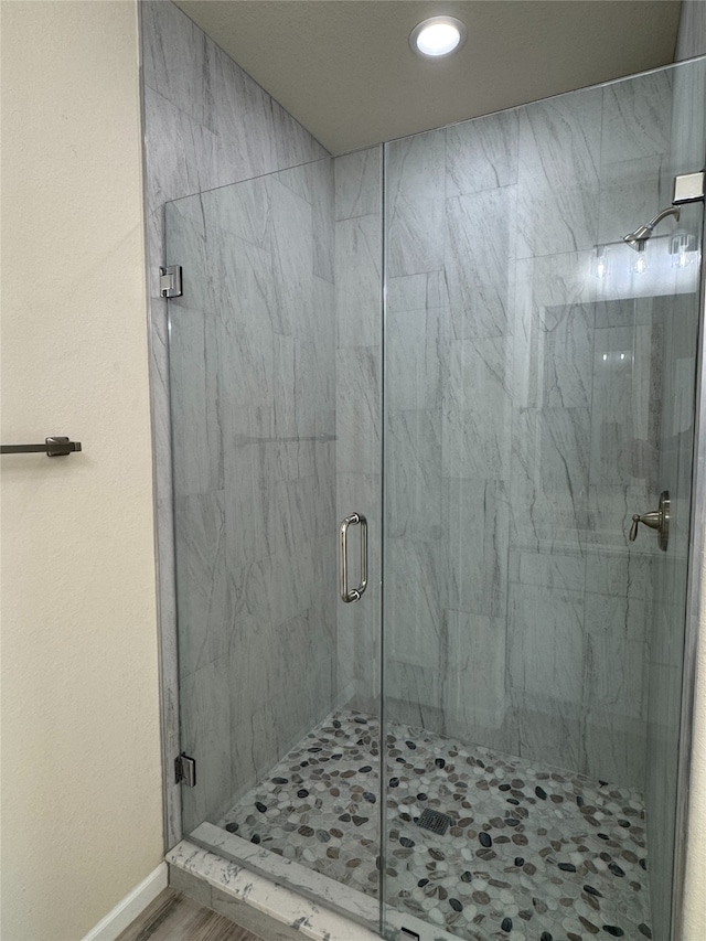 bathroom featuring baseboards, a marble finish shower, and recessed lighting
