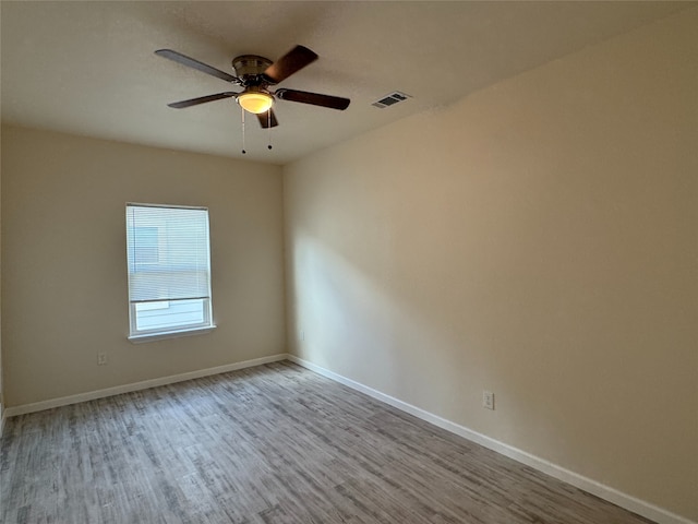spare room featuring baseboards, wood finished floors, visible vents, and a ceiling fan