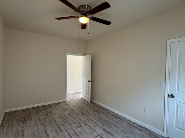 spare room with wood finished floors, a ceiling fan, and baseboards