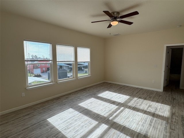 unfurnished room with visible vents, baseboards, wood finished floors, and ceiling fan