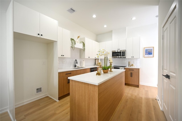 4009 New Orleans St A/B, Unit A/B Houston, TX 77020 - kitchen with a sink, stainless steel microwave, light wood-type flooring, visible vents, and decorative backsplash