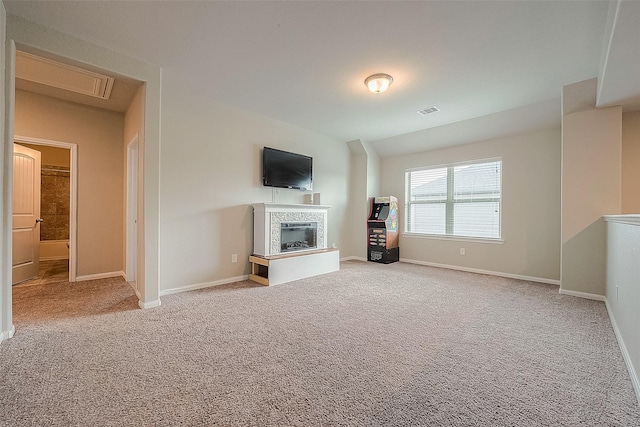 unfurnished living room with a glass covered fireplace, carpet, visible vents, and baseboards