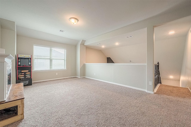 unfurnished living room with carpet floors, vaulted ceiling, visible vents, and baseboards