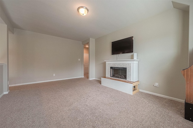 unfurnished living room with a glass covered fireplace, carpet floors, and baseboards