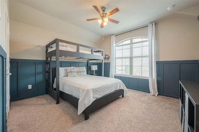 carpeted bedroom with lofted ceiling, a decorative wall, a wainscoted wall, and ceiling fan