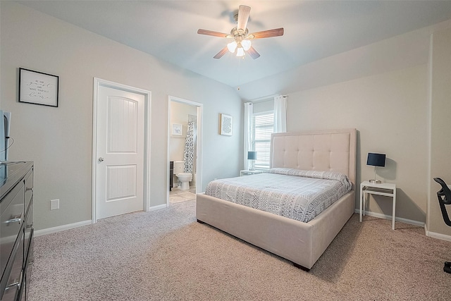 carpeted bedroom with vaulted ceiling, ensuite bath, baseboards, and ceiling fan