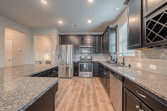 kitchen with light wood-style floors, tasteful backsplash, stainless steel appliances, and a sink