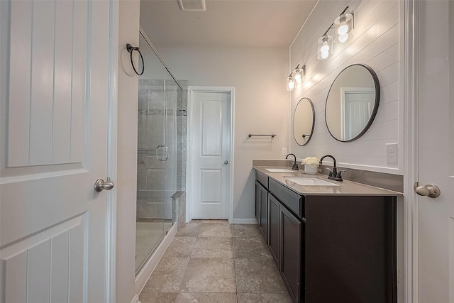 bathroom featuring a shower stall, baseboards, a sink, and double vanity