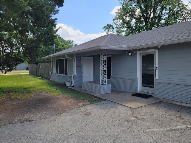 view of front of house featuring brick siding, a shingled roof, a front yard, and covered porch