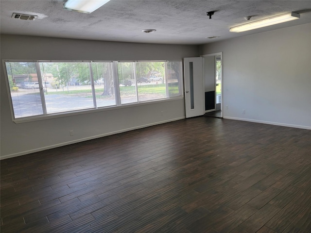 unfurnished room featuring dark wood finished floors, baseboards, and visible vents