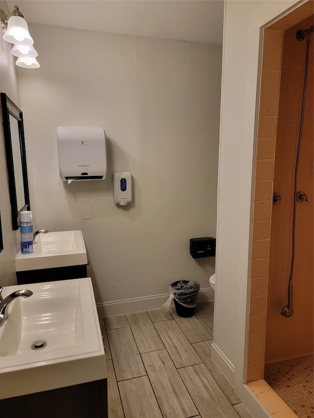 bathroom with wood finish floors, a sink, and tiled shower
