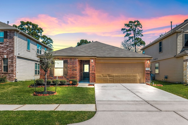 view of front of home featuring concrete driveway, a lawn, a shingled roof, an attached garage, and brick siding