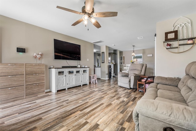 living room featuring light wood-style floors, a ceiling fan, and baseboards