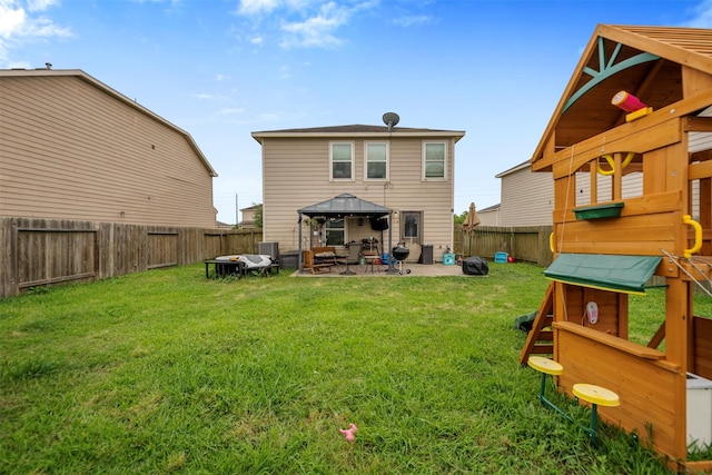 rear view of house featuring a gazebo, a fenced backyard, a yard, and a patio