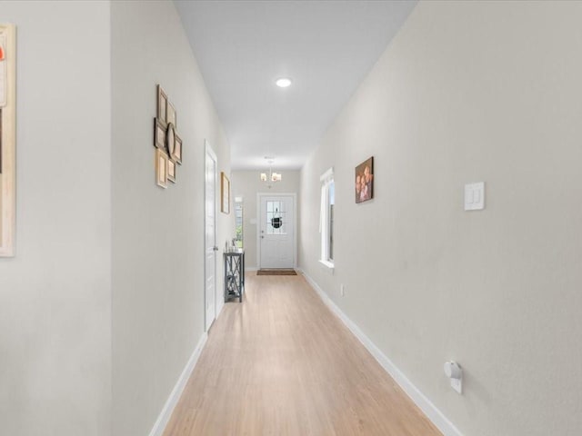 hallway featuring recessed lighting, light wood finished floors, baseboards, and an inviting chandelier