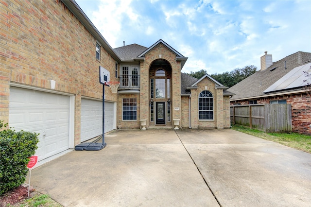 traditional-style house with brick siding, an attached garage, driveway, and fence