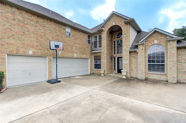traditional-style home featuring brick siding, driveway, a shingled roof, and a garage