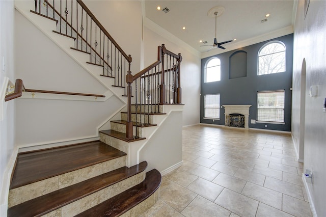 tiled foyer featuring crown molding, a ceiling fan, and stairs