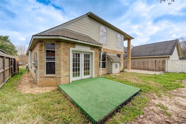 rear view of property with fence, a shingled roof, french doors, a patio, and a lawn