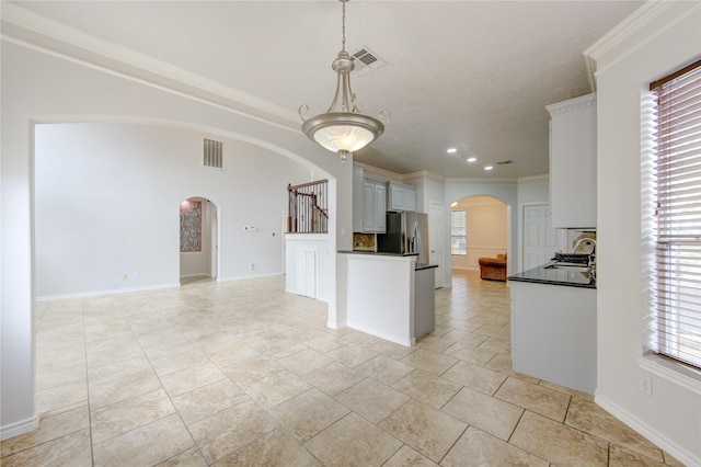 kitchen with dark countertops, visible vents, arched walkways, and open floor plan