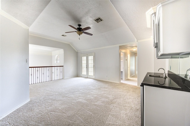 unfurnished living room featuring a sink, visible vents, light colored carpet, a ceiling fan, and ornamental molding