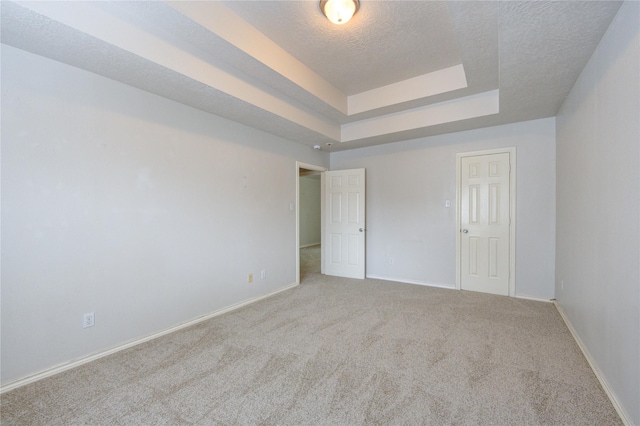 unfurnished bedroom featuring baseboards, carpet flooring, a textured ceiling, and a raised ceiling