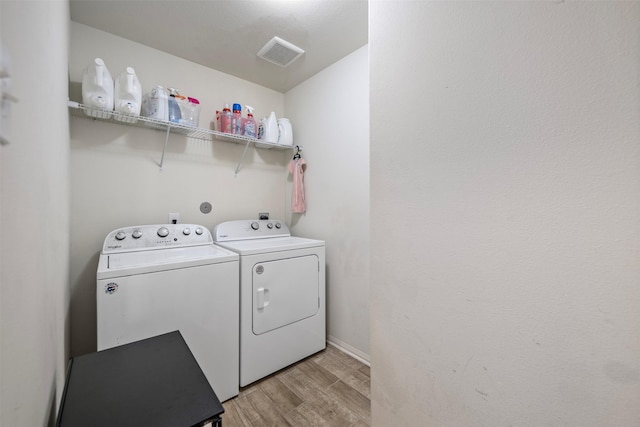 washroom with washing machine and clothes dryer, laundry area, light wood-style flooring, baseboards, and visible vents