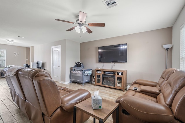 living room with baseboards, ceiling fan, light wood-type flooring, and visible vents