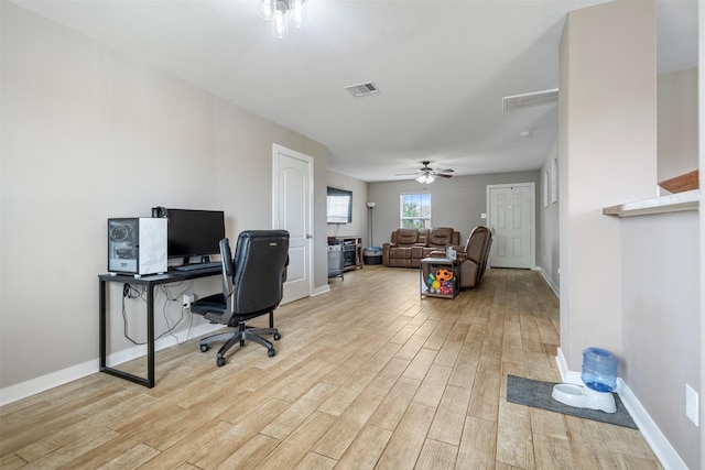 home office with visible vents, light wood-style floors, ceiling fan, and baseboards