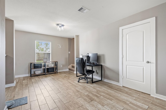 office space featuring visible vents, light wood-style flooring, and baseboards