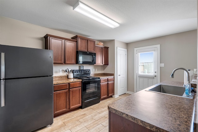 kitchen with dark countertops, wood tiled floor, a textured ceiling, a sink, and black appliances
