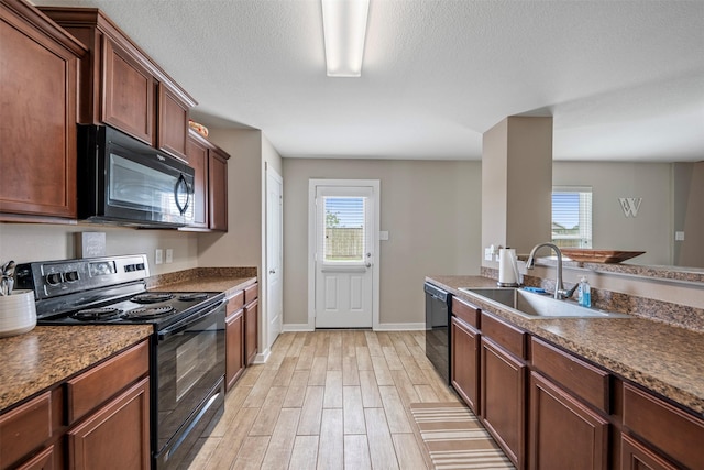 kitchen featuring baseboards, a wealth of natural light, a sink, and black appliances