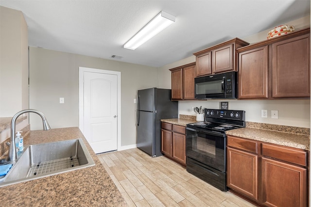 kitchen with visible vents, a sink, light wood-style floors, and black appliances