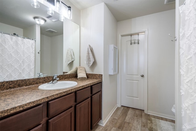 full bath with visible vents, wood finished floors, vanity, baseboards, and toilet
