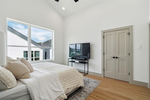 bedroom with light wood finished floors, recessed lighting, a ceiling fan, a closet, and high vaulted ceiling