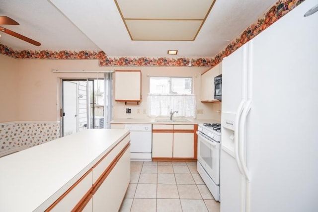 kitchen with a sink, plenty of natural light, white appliances, ceiling fan, and light countertops