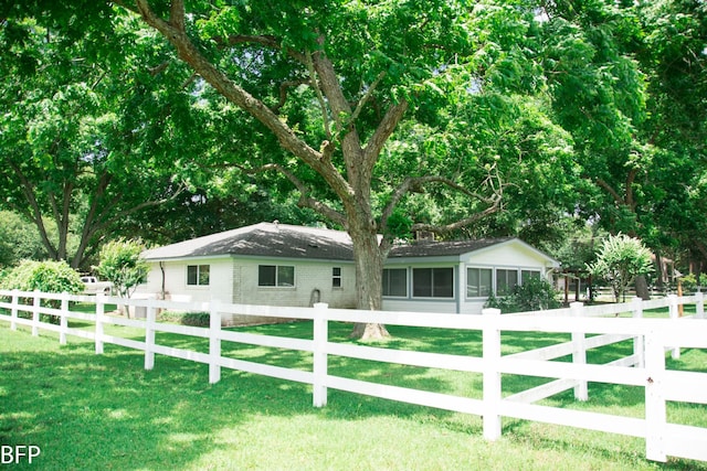 view of front facade featuring a fenced front yard, a sunroom, and a front lawn