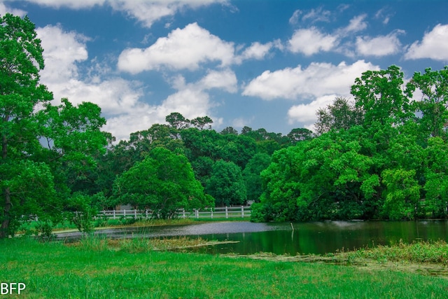 view of water feature featuring fence and a forest view