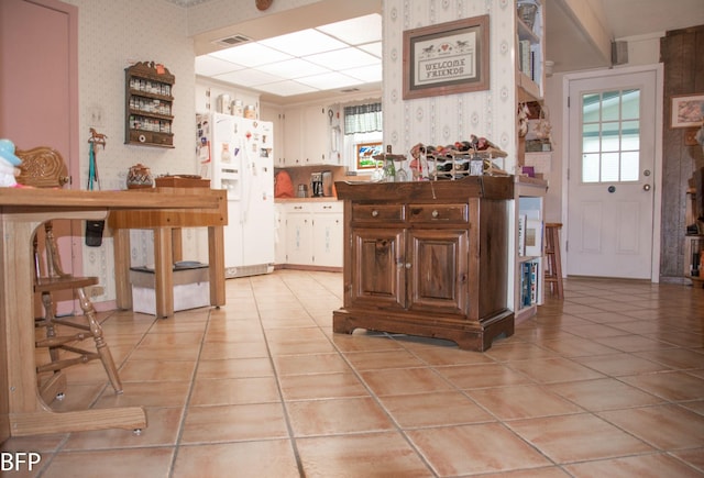 bar with light tile patterned floors, wallpapered walls, visible vents, and white refrigerator with ice dispenser